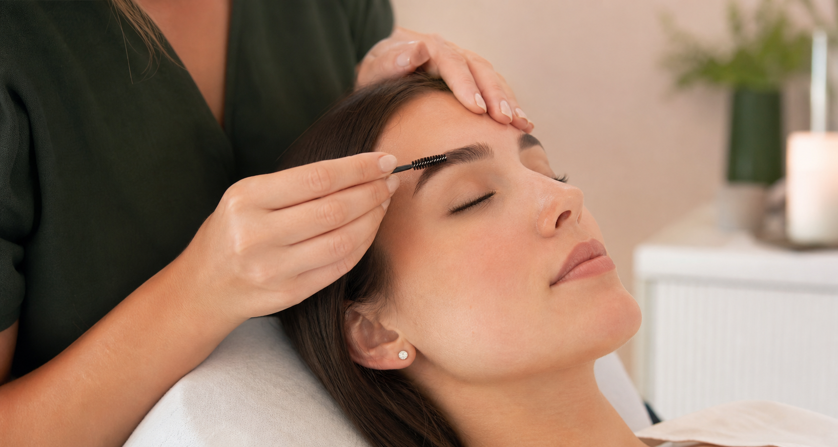 Beauty therapist brushing a client's eyebrow during a lash and brow appointment